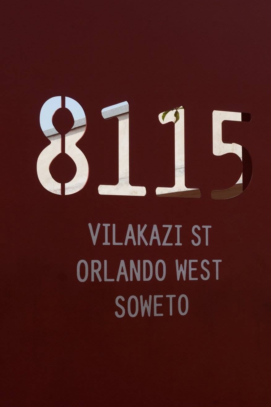 Township tour Soweto: roestrode gevel met het uitgesneden huisnummer 8115 van Mandela House aan Vilakazi Street, Orlando West